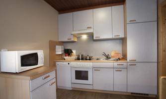A modern kitchen with bright cabinets and a practical layout. It includes a microwave, a stove, and various cooking utensils.