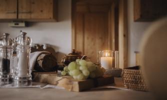 A beautiful table with fresh grapes, bread, and a candle. The wooden surface conveys a cozy atmosphere.