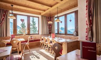 A cozy restaurant with wooden decor and large windows. The tables are decorated and offer a view of the surrounding landscape.