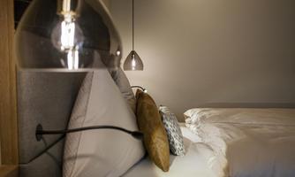 A modern bedroom with cozy pillows and stylish lighting. The room exudes calm and elegance.