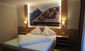 A modern bedroom with a large bed and artistic wall decoration. The lighting creates a cozy atmosphere.