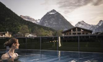 A relaxing thermal bath with a view of majestic mountains. The woman enjoys the scenery in the evening ambiance.