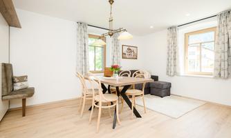 A bright and modern dining room with a wooden table and several chairs. Large windows let in plenty of light and give the room a friendly atmosphere.