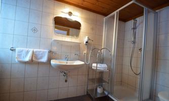 A modern bathroom with a shower cubicle, sink, and mirror. Towels are neatly hung next to the sink.