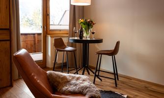 A stylish living room with a comfortable armchair and a small table. The windows offer a view outside and create a bright, inviting atmosphere.