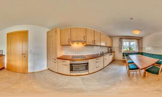 A modern kitchen with wooden cabinets and a dining table. The room is bright and cheerful with plenty of storage space.