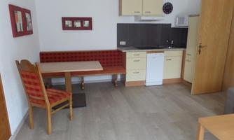 A bright, modern kitchen with a dining area. The furniture is designed to be simple and functional.