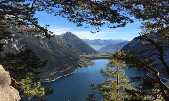A picturesque mountain landscape with a clear blue lake. Surrounded by tall, green trees and majestic mountains in the background.