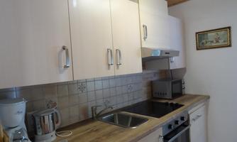 A modern kitchen with bright cabinets and a stainless steel stove. Various kitchen appliances and a sink can be seen on the countertop.