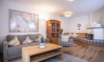 A cozy living room with a gray sofa, a wooden table, and a stylish sideboard. The warm atmosphere is enhanced by bright colors and appealing decorations.