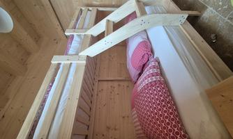 A cozy room with a wooden bunk bed. The beds are equipped with colorful pillows and blankets.