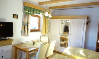 A cozy room with two single beds, a table and chairs. Brightly lit with wooden details and a television.