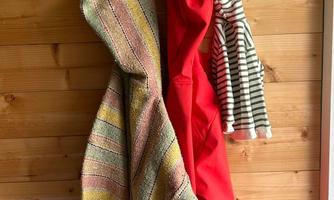 Three pieces of clothing hang on a space-saving wooden hook. The background is a wooden wall, and above the hook is a cow motif.