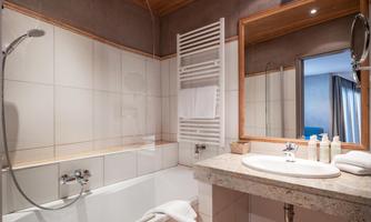 A modern bathroom with a bathtub and a sink. There is a towel holder and a large mirror.