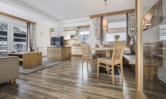 A modern apartment with an open living and dining area. Large windows let in plenty of light and the wooden floor gives a cozy atmosphere.