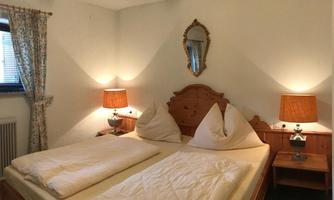 A cozy bedroom with a double bed and two nightstands. The warm lamps and curtains create an inviting atmosphere.