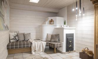 A cozy room with wood paneling and a comfortable seating area. The room features a stove and modern pendant lights.