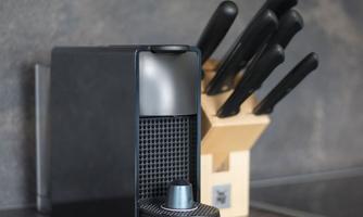 A stylish kitchen machine from Krups stands next to a wooden block with kitchen knives. The modern design fits well into any kitchen.