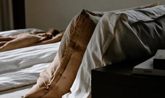 A cozy bedroom with a bed and pillows in gentle colors. The light creates a relaxed atmosphere.