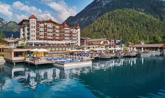 A beautiful resort by the water with modern facilities. In the background, picturesque mountains and a clear sky can be seen.
