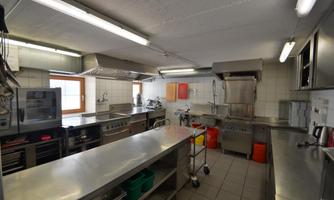 A modern kitchen with stainless steel surfaces and extensive equipment. Plenty of space for cooking and preparing meals.