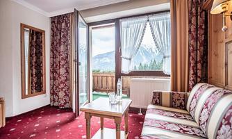 A cozy room with a sofa and a table. The windows offer a beautiful view of the mountains and nature.
