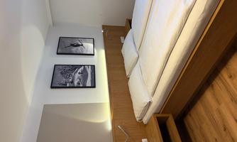 A modern bedroom with two beds and wooden decor. Black-and-white pictures of winter scenes hang on the walls.