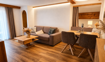 A modern living room with a cozy sofa and a dining table. Bright colors and wooden details give the room a friendly atmosphere.