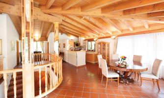 A modern, bright living room with wooden beam ceiling. There is a dining table and a cozy atmosphere.