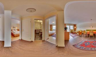 A bright living space with an open kitchen and a dining area. The floor is covered with a carpet and there are cozy furnishings.