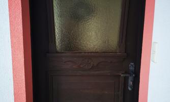 A brown wooden door with a glass upper part. The door is located in a red frame.