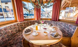 A cozy dining area with a round table and a view of the mountains. The table is lovingly set with food and drinks.