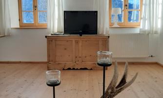 A cozy room with two windows and a television. On the table lies a deer antler with candle holders.