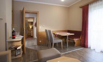 A cozy room with a dining area and one or more chairs. The light-filled ambiance is accentuated by a window front and soft colors.