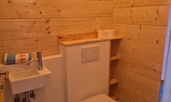 A small bathroom with wood paneling. It contains a sink and a toilet.