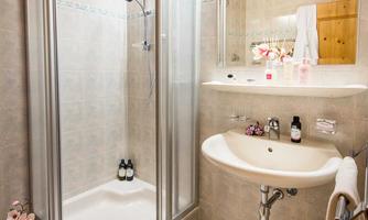 A modern bathroom with a shower cabin and a sink. The furnishings are bright and inviting, with decorative elements.