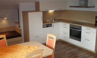 A modern kitchen with light furniture and wooden surfaces. The dining area is simply furnished and invites you to linger.