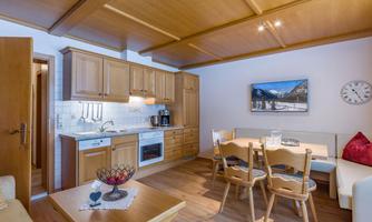 A cozy kitchen with wooden cabinets and a dining area. The room is bright and cheerfully designed.