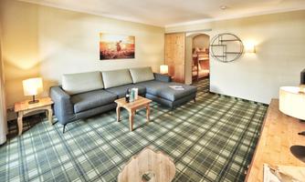 A bright living room with a gray couch and a small table. The room has a checked rug and a warm atmosphere.