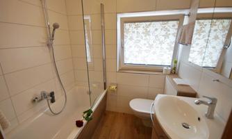 A modern bathroom featuring a bathtub and a separate shower. Bright tiles and a large window create a friendly atmosphere.