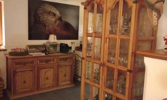 A cozy room with wooden furniture and a large display cabinet. A picture of an eagle hangs on the wall.