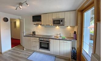 A modern kitchen with light wood cabinets and a stove. There is a window with a view outside and a pleasant, inviting atmosphere.