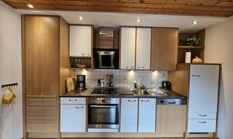 A modern kitchen with wood-colored and white cabinets. It is well-equipped and has a bright, inviting atmosphere.