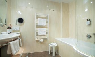 A modern bathroom with a bathtub and a sink. Towels are neatly arranged on a towel rack.