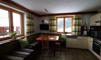 A modern kitchen with a cozy dining area. Large windows provide a view of the wintry landscape.
