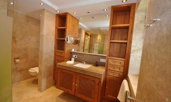 Modern bathroom with wooden cabinets and a stylish sink. The walls are in neutral colors and there is a shower in the background.