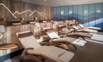 A modern relaxation room with comfortable lounge chairs and warm light. The walls are designed in soft shades of blue and wood tones to create a calm atmosphere.