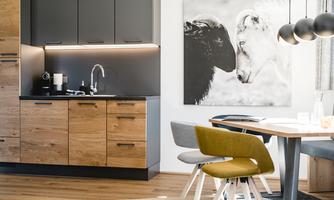 A modern kitchen with wooden and gray cabinets. On the wall hangs a picture of two animals standing close to each other.