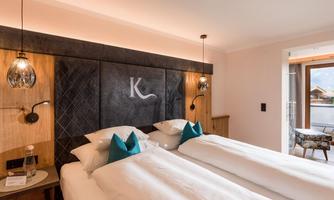 A modern bedroom with two single beds and stylish accessories. Large windows let in plenty of light and offer a view outside.