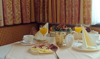 A beautifully set table with breakfast. There is fresh fruit, drinks, and various dishes.